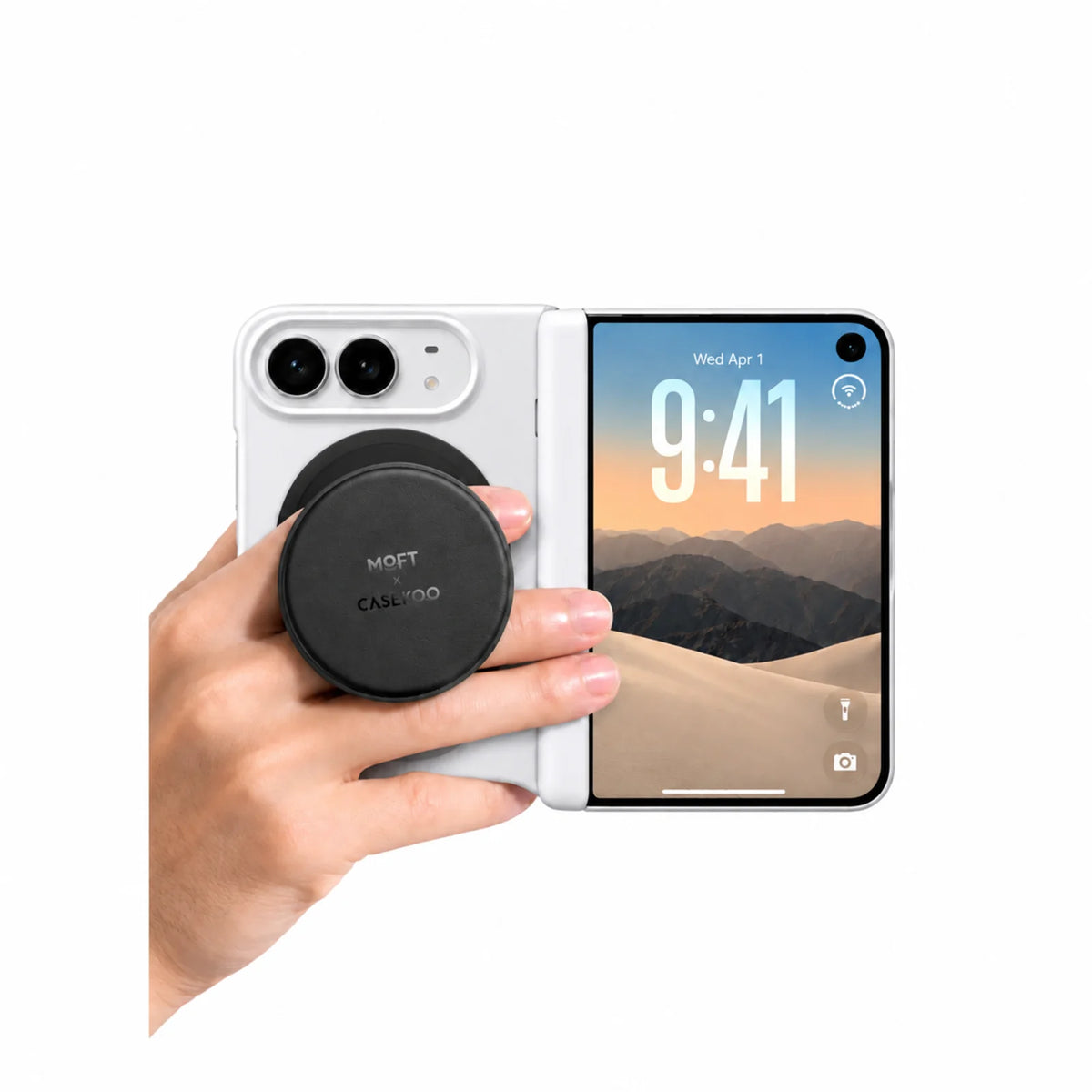 Hand holding a white foldable phone with a black MOFT × CASEKOO magnetic stand and grip